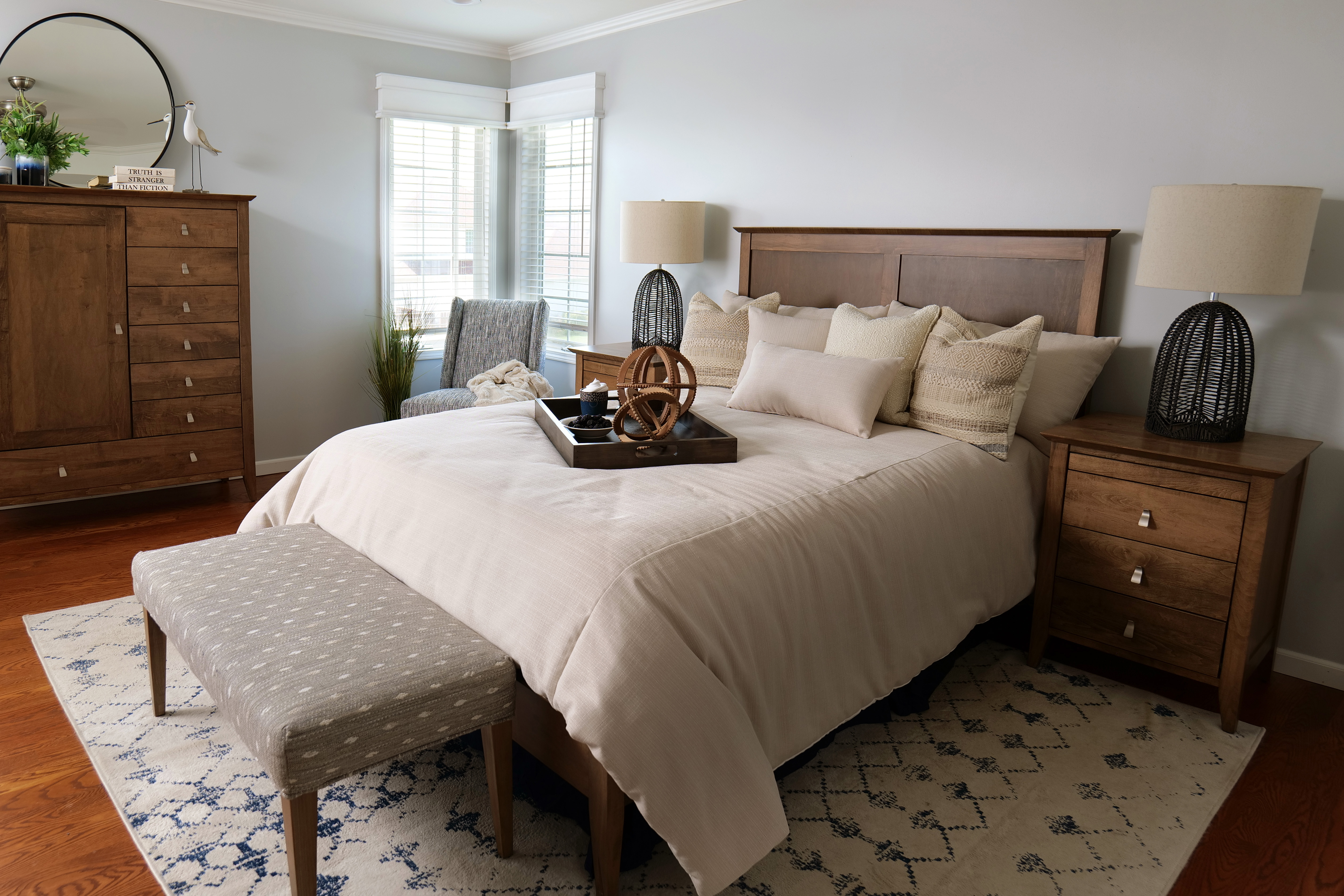 A beautiful modern bedroom with a large chest of drawers, matching side tables , and a large king size bed with foot board.