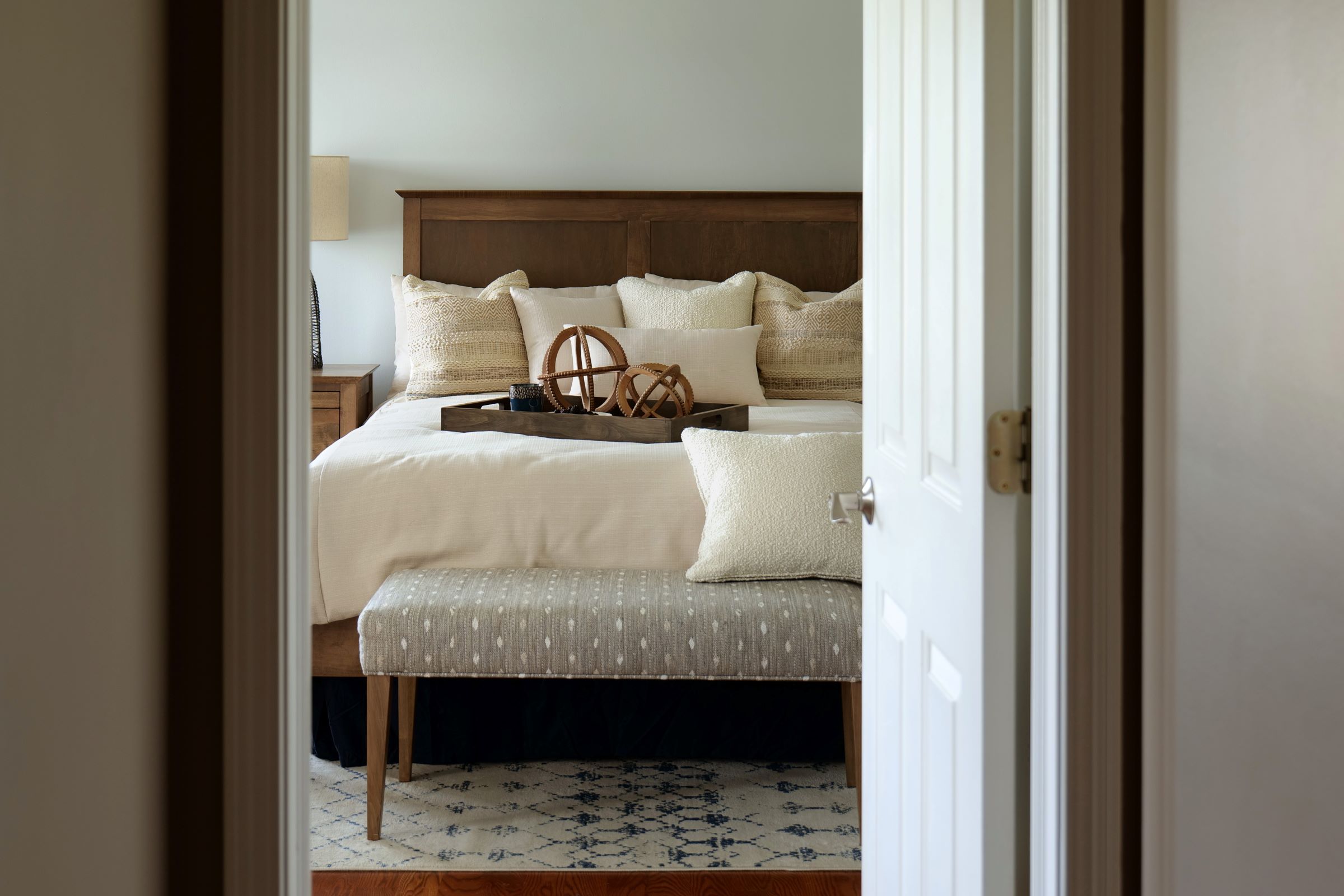 The Matrix Panel Bed and Alex Bench sit nestled in a cozy bedroom seen through an open door