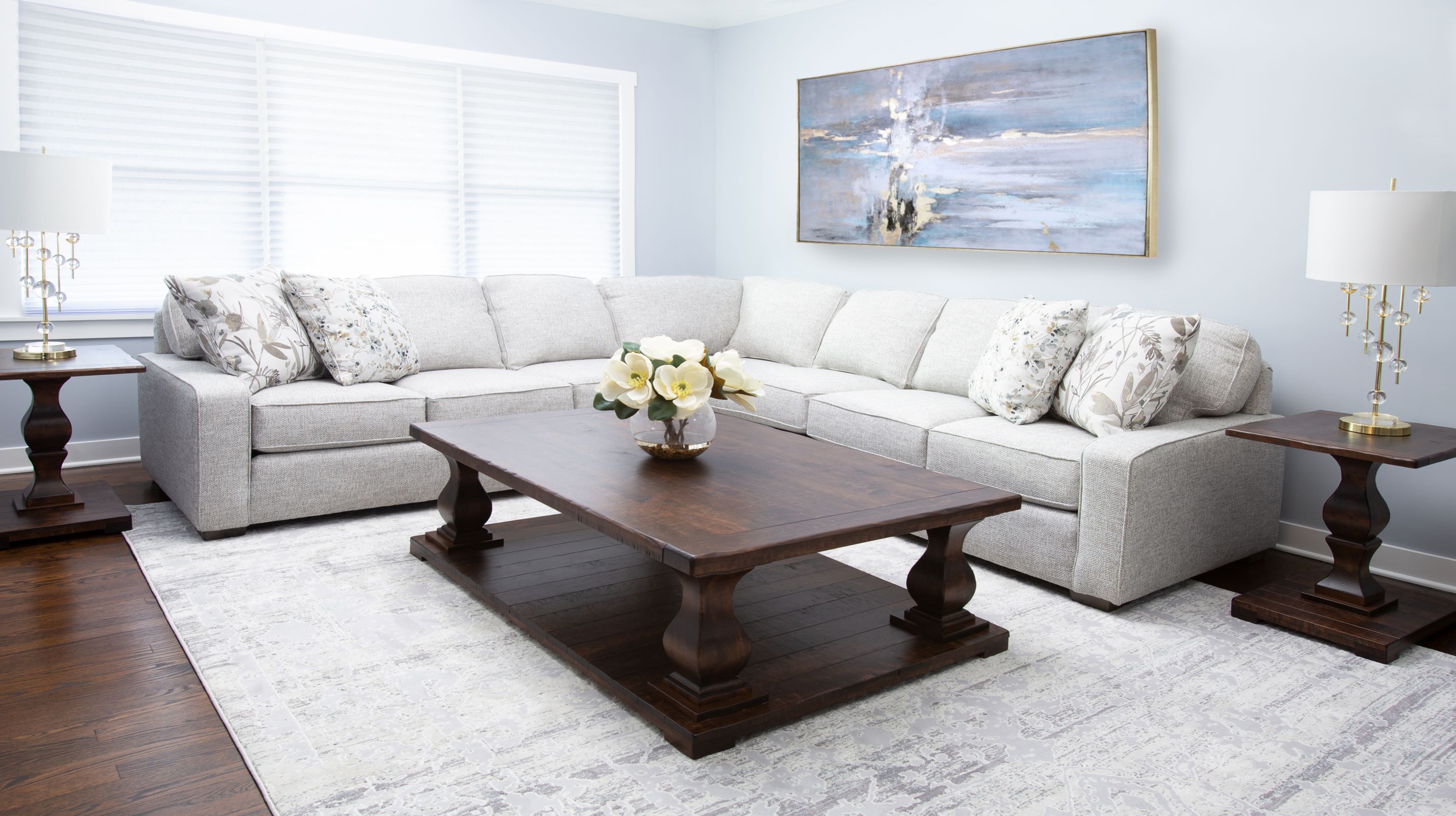 The Remy Coffee Table and End Table sit nestled within a large white upholstered sectional in a bright light blue living room