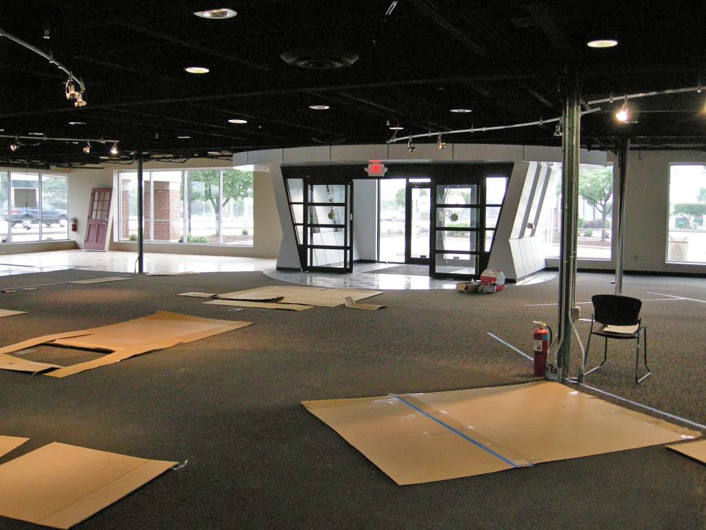 A wide angle shot of a furniture showroom under construction with pieces of cardboard and temporary carpet covering the floor