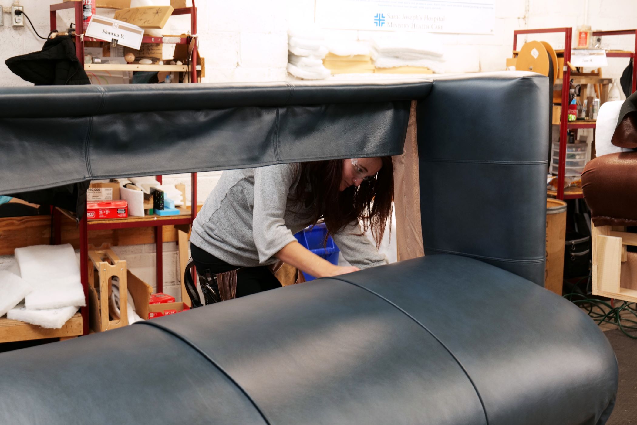 An upholstery Craftsmen from Marshfield Furniture works putting the leather covering on a sofa