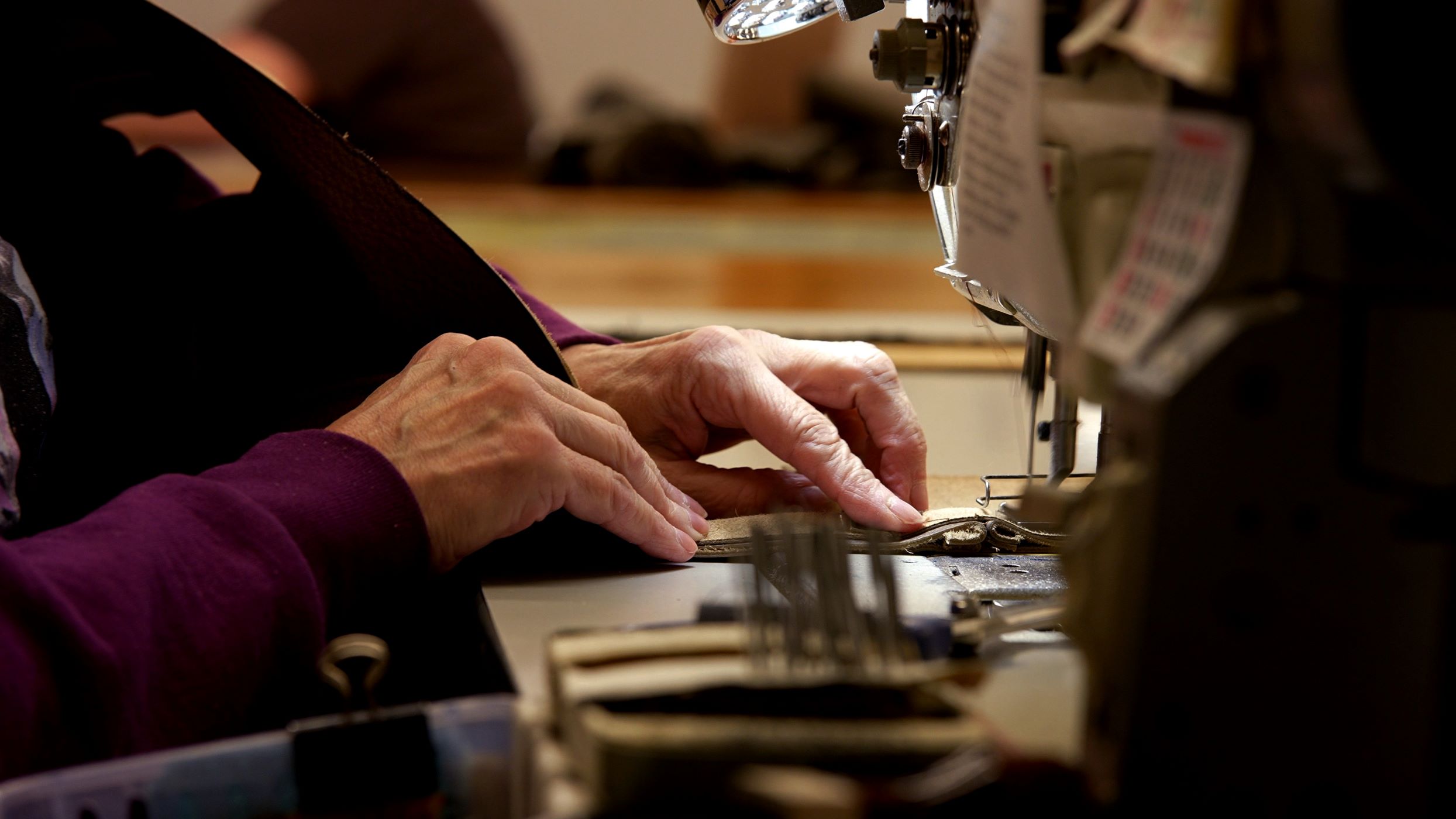 A seamstress from Marshfield Furniture Shop sews together upholstery for a piece of furniture