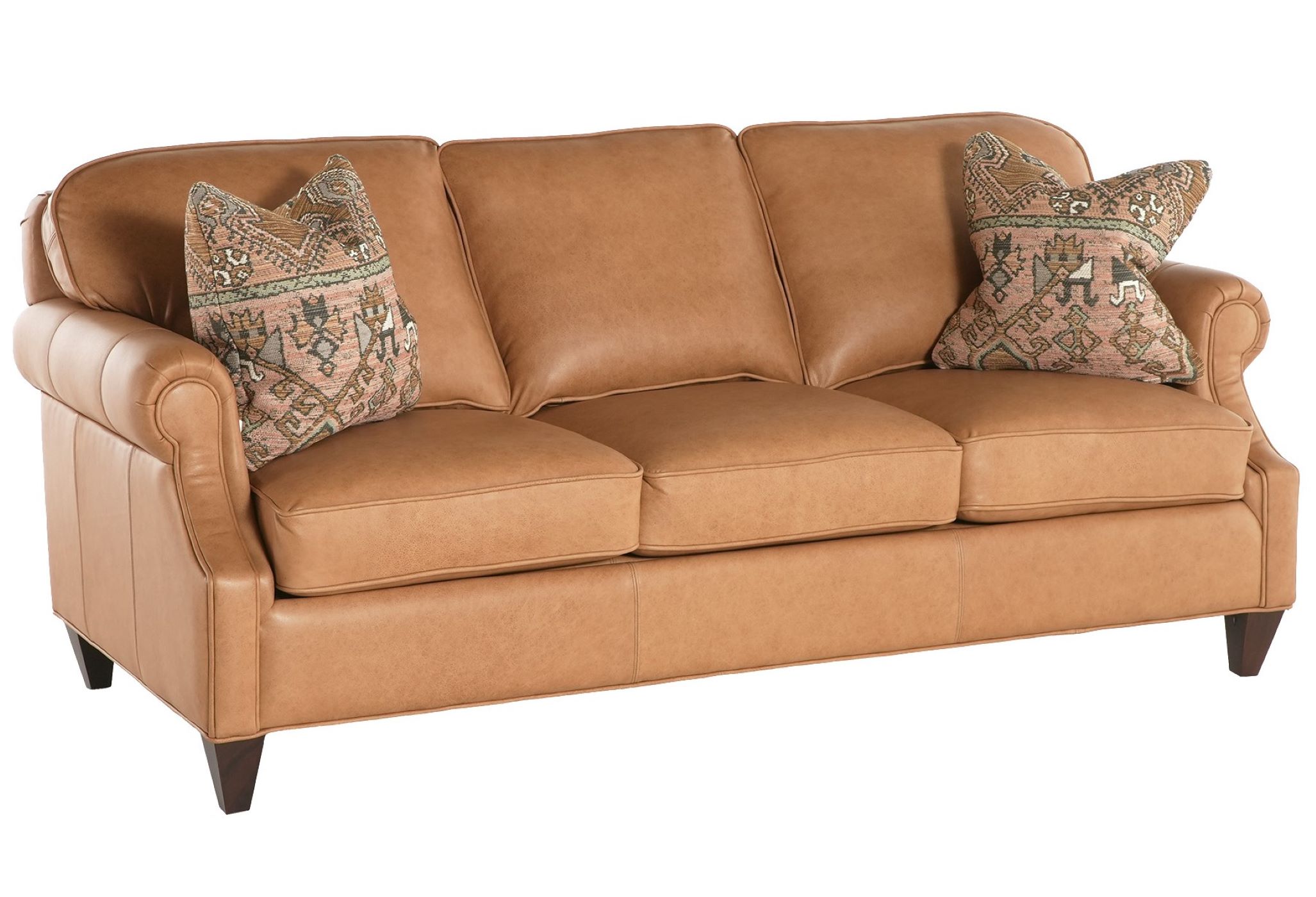 The Charles Sofa in light brown leather with dark stained legs and decorative throw pillows sits on a field of white