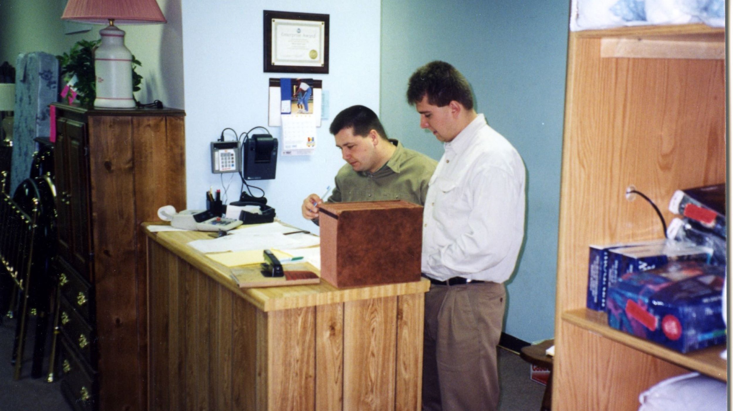 In 1995, Ben and Arvid Huth stand behind a wood veneered counter as they work to organize documents for the store.