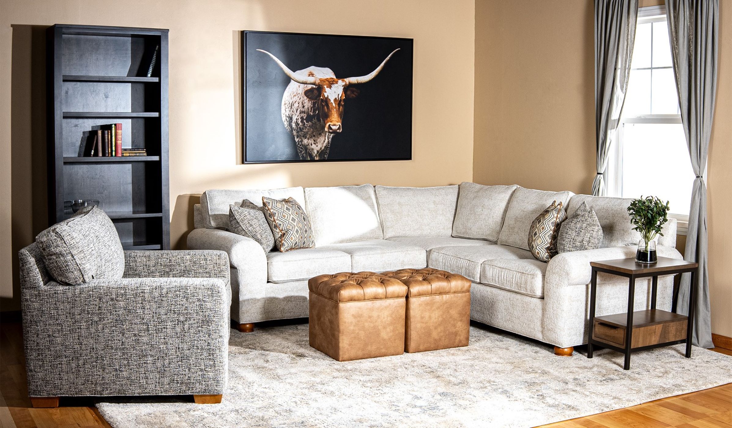 The JYS3 Collection from Penny Mustard decorates a large living room with a bright window and a painting of a texas steer on the wall